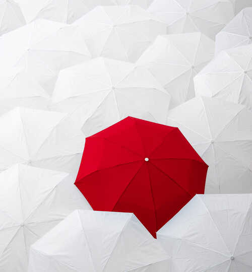 One red umbrella amoung many white umbrella to illustrate marketing standing out from the crowd