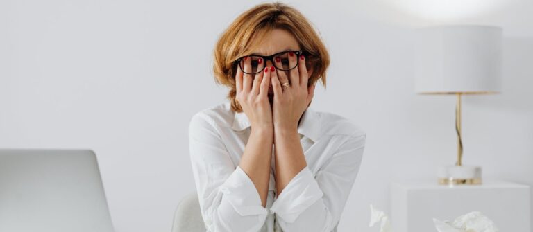 A woman holding her hands over her face represents the frustration of finding old stats that are portrayed as being new.