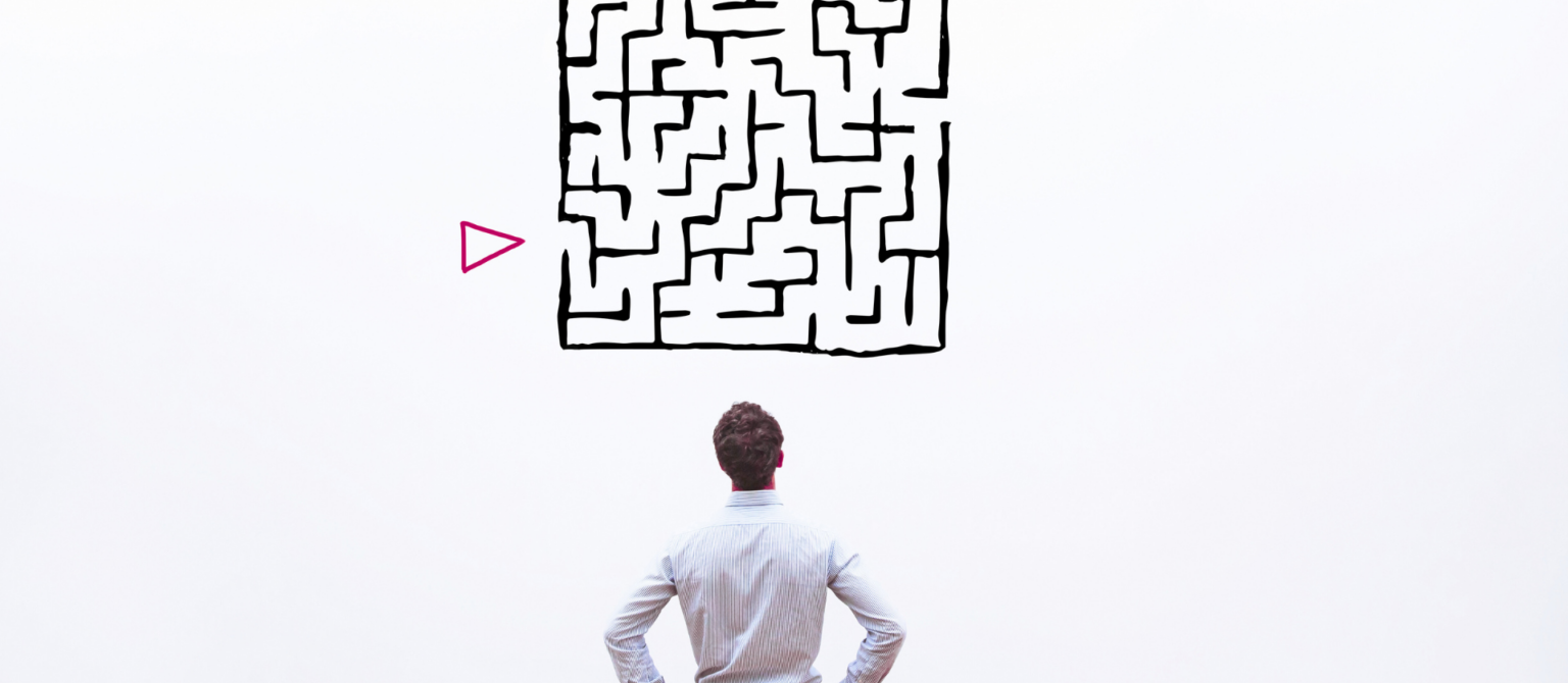 A man looking at a maze on a wall represents the challenge of simplifying complex tech content.